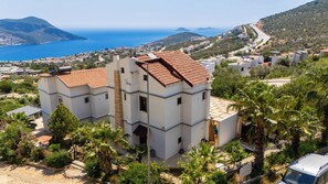 A multi-story building with a red-tiled roof, surrounded by greenery and overlooking a coastal landscape. - Villa with stunning sea view and private pool (Kaş)