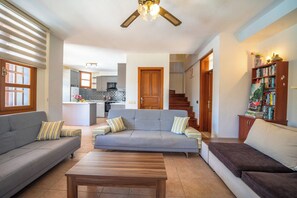 A living room with a grey sofa, a brown sofa, a wooden coffee table, and a bookshelf. - Villa with stunning sea view and private pool (Kaş)