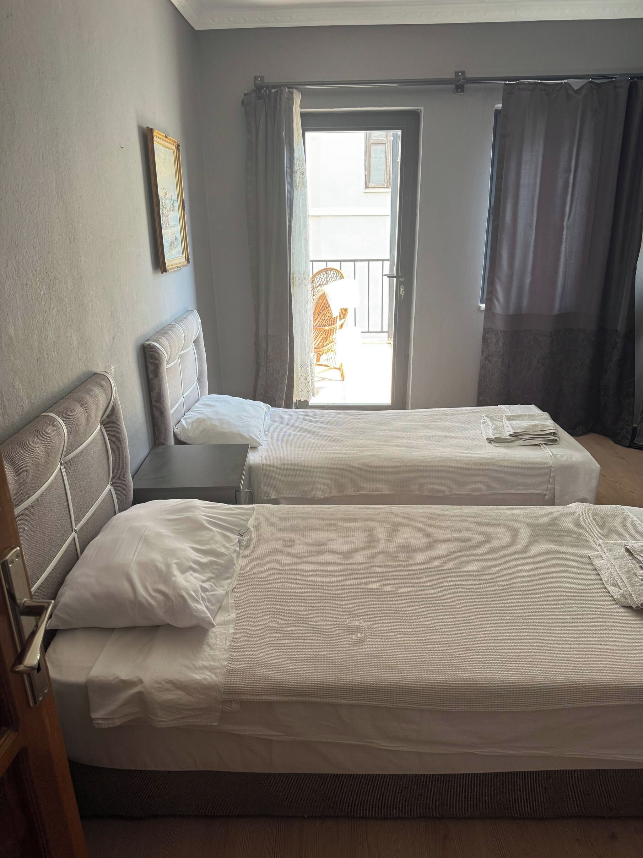 Quarto de hotel com duas camas, porta para uma varanda e quadro pendurado na parede.