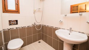 Un baño con inodoro, lavamanos, ducha y espejo.