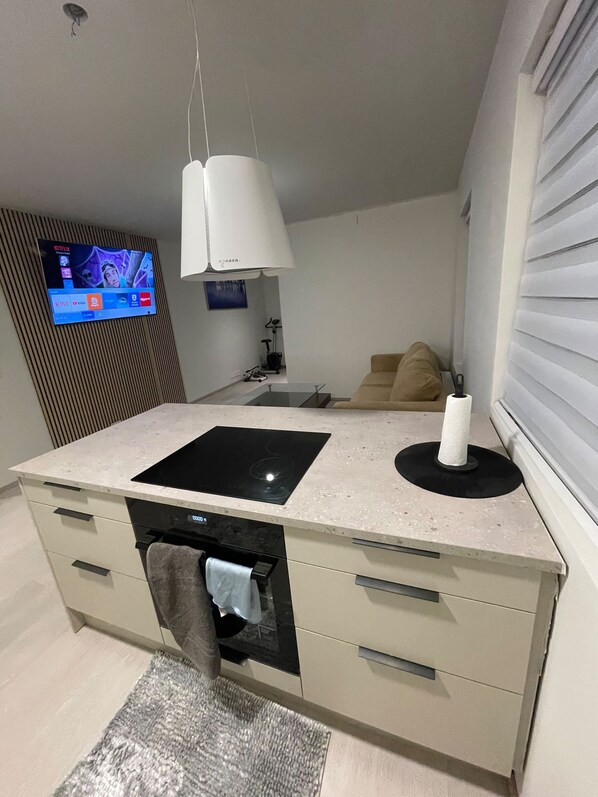 Eine moderne Küche mit Einbauofen, Flachbildfernseher an der Wand und Essbereich mit einer Couch.
