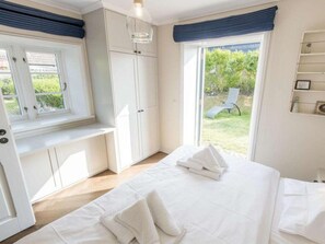 A bedroom with a bed, a window, a bench, and a view of the outdoors. - Holiday Apartment in Westerland With Sauna (Sylt)