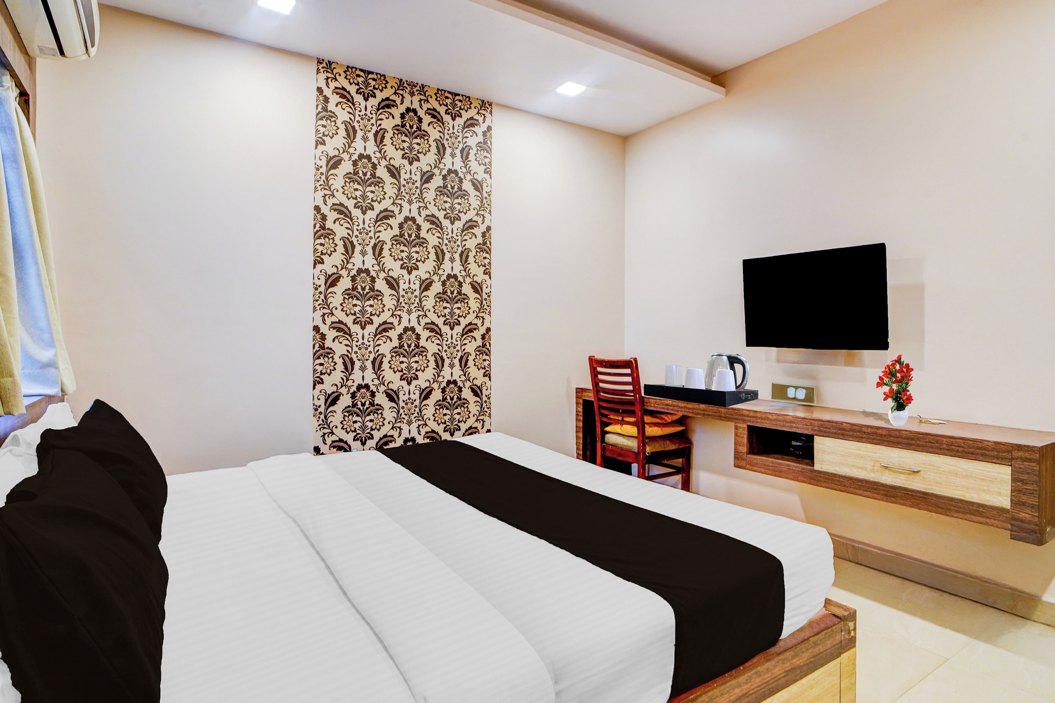 A hotel room with a bed, a desk, a chair, a television, and a window with curtains.