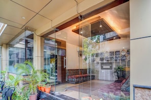 A modern interior with glass partitions, a seating area, and a wall displaying various items.