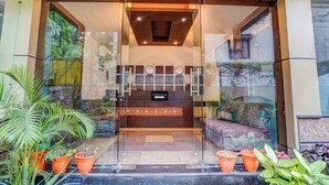 A reception area with a glass door, a reception desk, and a wall with clocks. - Townhouse Madan Mahal Railway Junction (Jabalpur)