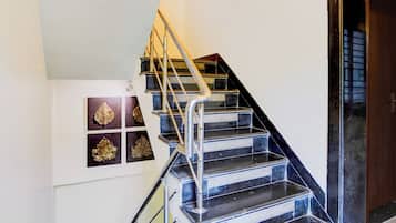 Una escalera con barandales de metal y pasamanos, que lleva a un rellano con una puerta.