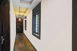 A hallway with a wooden door, a window with bars, and a ceiling with recessed lighting.
