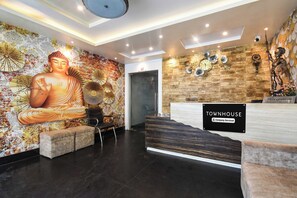 En reception med en Buddha-statue, et ur og et skilt, der viser udtjekningstidspunktet.