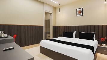 Een hotelkamer met een bed, nachtkastje en een bureau met stoel.