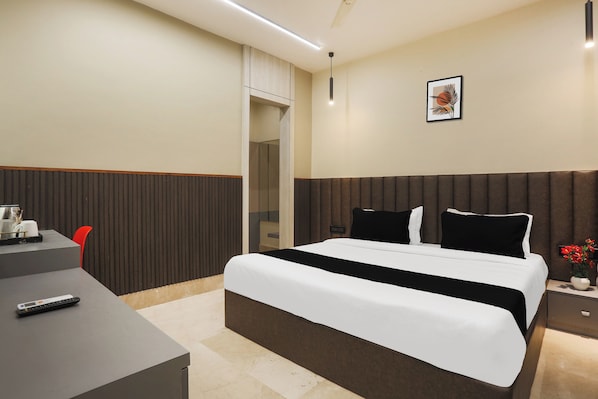 A hotel room with a bed, bedside table, and a desk with a chair.
