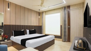 Habitació d'hotel moderna amb un llit gran, una taula de treball, una tetera i una televisió.