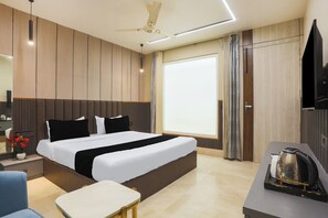 Una habitación de hotel moderna con una cama grande, un escritorio, un hervidor de agua y un televisor.