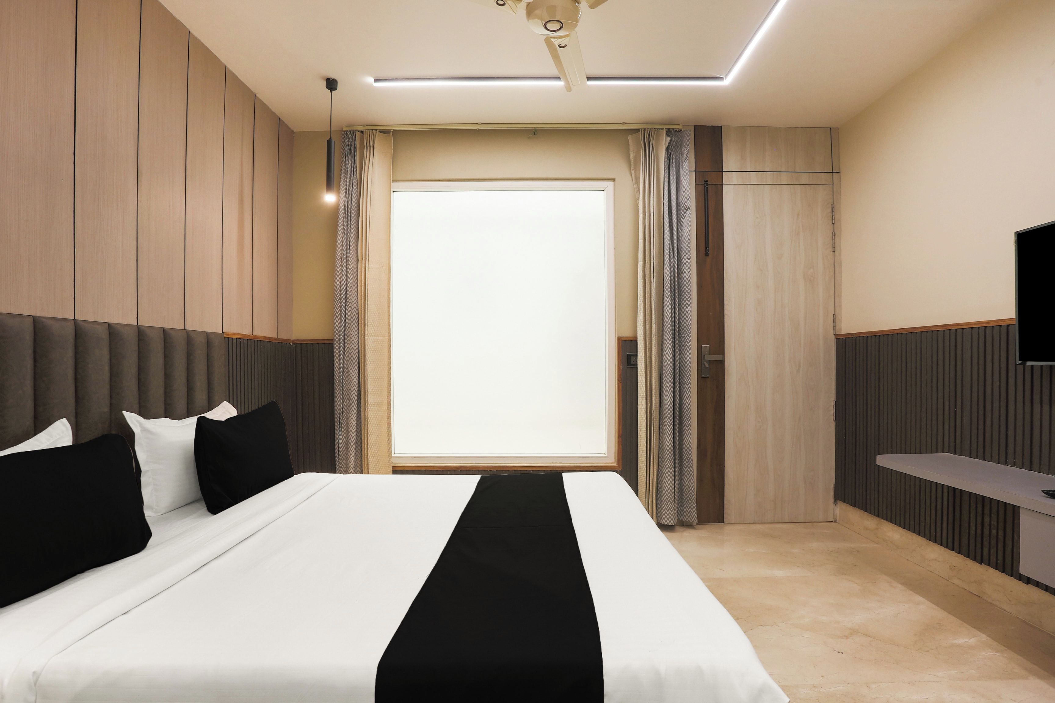 Een moderne hotelkamer met een groot bed, een flatscreen televisie en een raam met gordijnen.