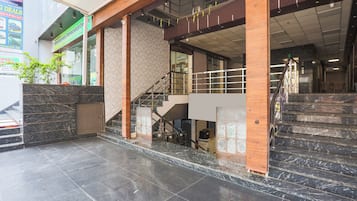 A commercial building with a staircase, marble flooring, and a green signboard.