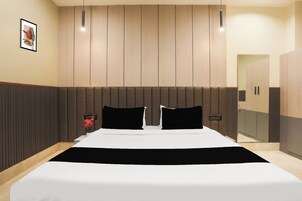 A modern bedroom with a large bed, a wooden headboard, and a bedside table with a vase of flowers.