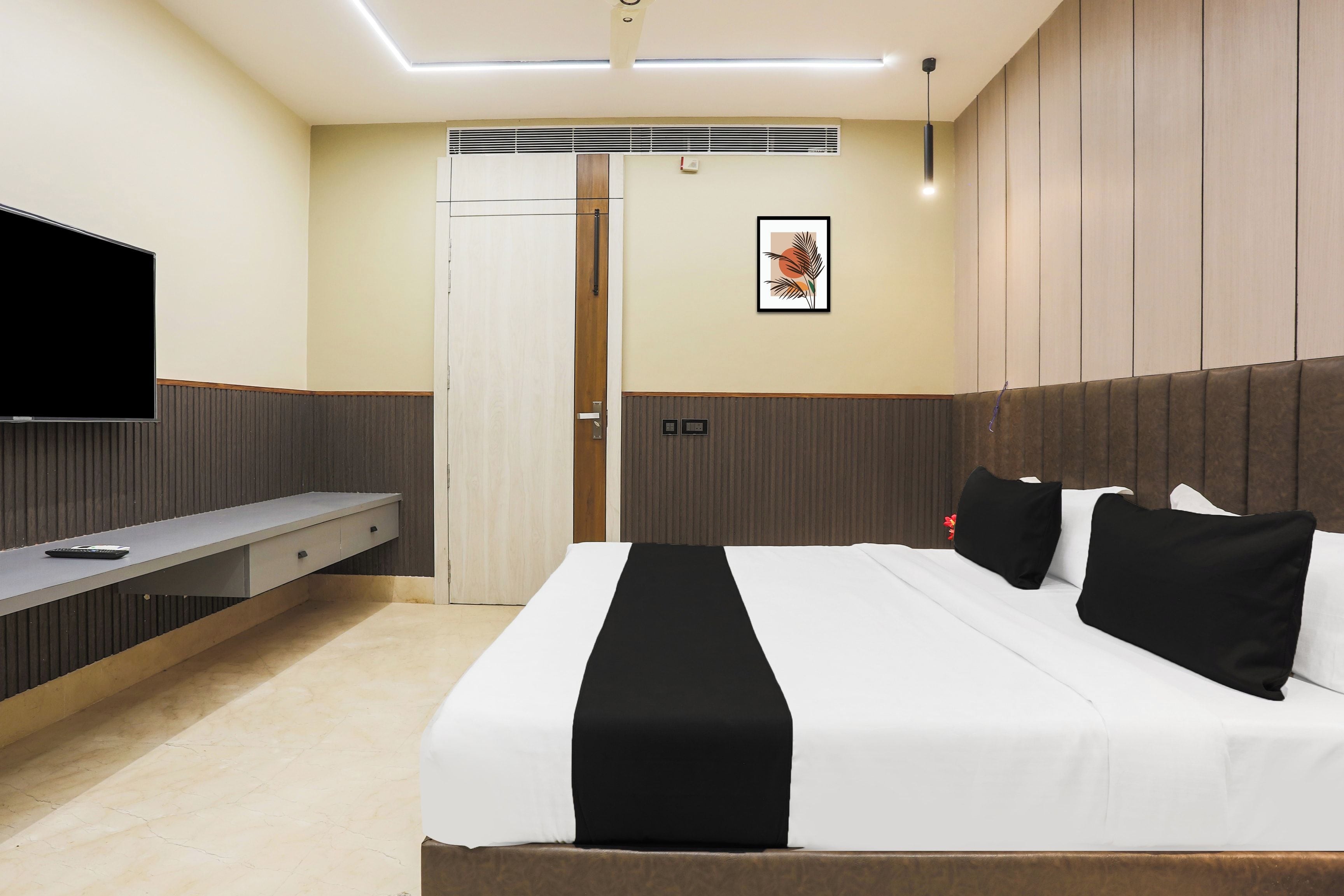A hotel room with a bed, a TV, a desk, and a door.