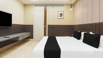 A hotel room with a bed, a TV, a desk, and a door.