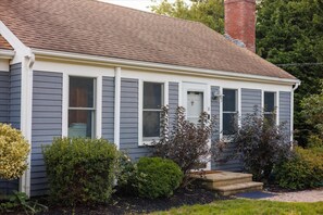 A two-story house with a grey siding exterior, a brown shingled roof, and a brick chimney. - Yarmouth Port Oasis Near Ocean and Beach Fun (Yarmouth)