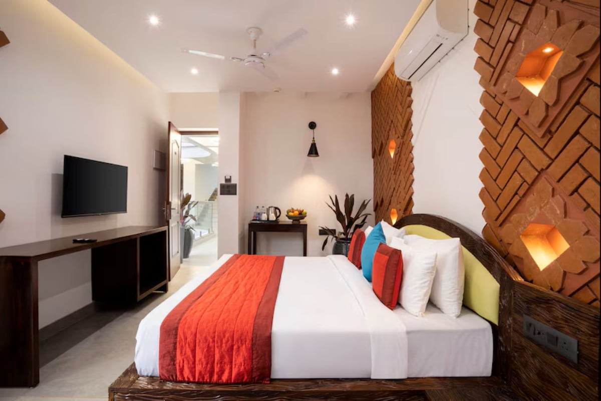 Quarto de hotel moderno com cama, televisão e decoração na parede.