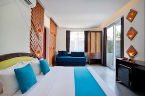 Quarto de hotel com cama, sofá, escrivaninha e vista para o exterior.