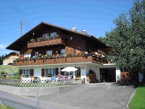 A two-story wooden building with a balcony, a covered outdoor seating area, and a fenced garden. - Chalet Sunneschyn Appartement/Fewo, Dusche oder Bad, WC 2-Bett Wohnung by Interhome (Schwanden ob Sigriswil)