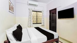 A bedroom with a bed, an air conditioning unit, a window with a curtain, and a door. - Townhouse Bangalore Goraguntepalya (Bengaluru)