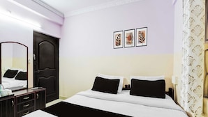 A hotel room with a bed, a dresser, a mirror, and a wall with three framed pictures. - Townhouse Bangalore Goraguntepalya (Bengaluru)
