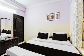 Ein Hotelzimmer mit einem Bett, einem Schminktisch, einem Spiegel und einer Wand mit drei gerahmten Bildern.