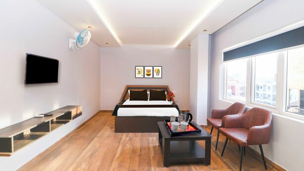 A modern hotel room with a bed, a TV, a desk, a chair, and a window. - Townhouse Ranchi Tapovan Mandir (Ranchi)