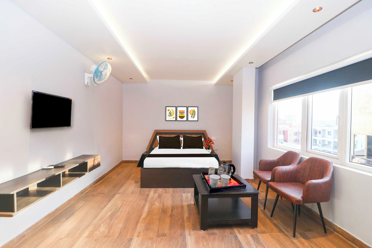 Una habitación de hotel moderna con cama, televisor, escritorio, silla y ventana.