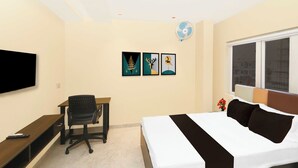 A hotel room with a bed, desk, chair, TV, artwork, and a window. - Townhouse Ranchi Tapovan Mandir (Ranchi)