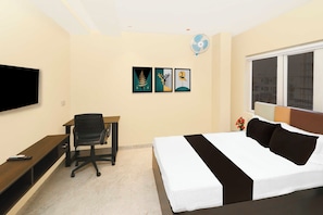 Habitación de hotel con cama, escritorio, silla, televisor, obra de arte y ventana.