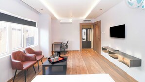 A modern living room with a sofa set, a coffee table, a TV mounted on the wall, and a wooden floor. - Townhouse Ranchi Tapovan Mandir (Ranchi)