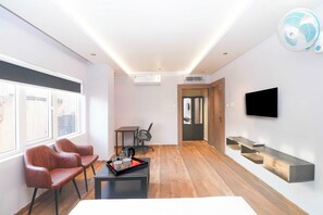 Una sala de estar moderna con un conjunto de sofá, una mesa de centro, un televisor montado en la pared y piso de madera.