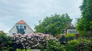 Et rundt træbord med en potteplante, to træstole og en brostensbelagt terrasse.