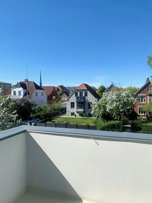 Un barrio residencial con varias casas, una aguja de iglesia y un cielo azul despejado.
