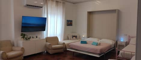Una habitación de hotel con cama, escritorio, silla, televisor y un cuadro en la pared.