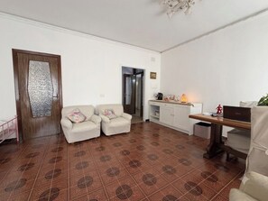 A living room with a sofa, a dining table, and a kitchen area.