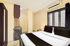 Habitación de hotel con cama, mesita de noche, ventana con barrotes, unidad de aire acondicionado y calentador de pared.