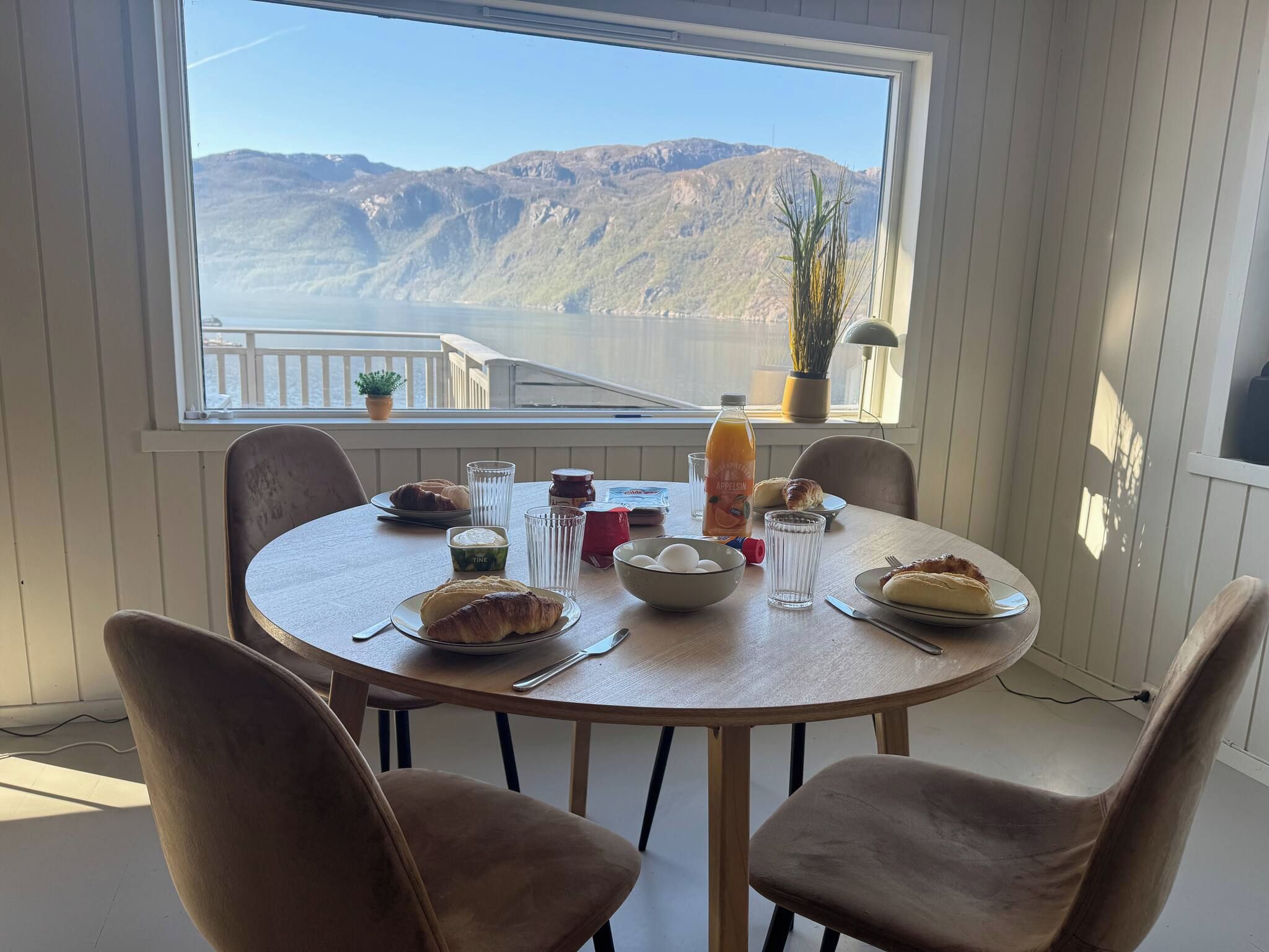 A dining table with plates of food, glasses, and a bottle, set against a window with a mountain view.