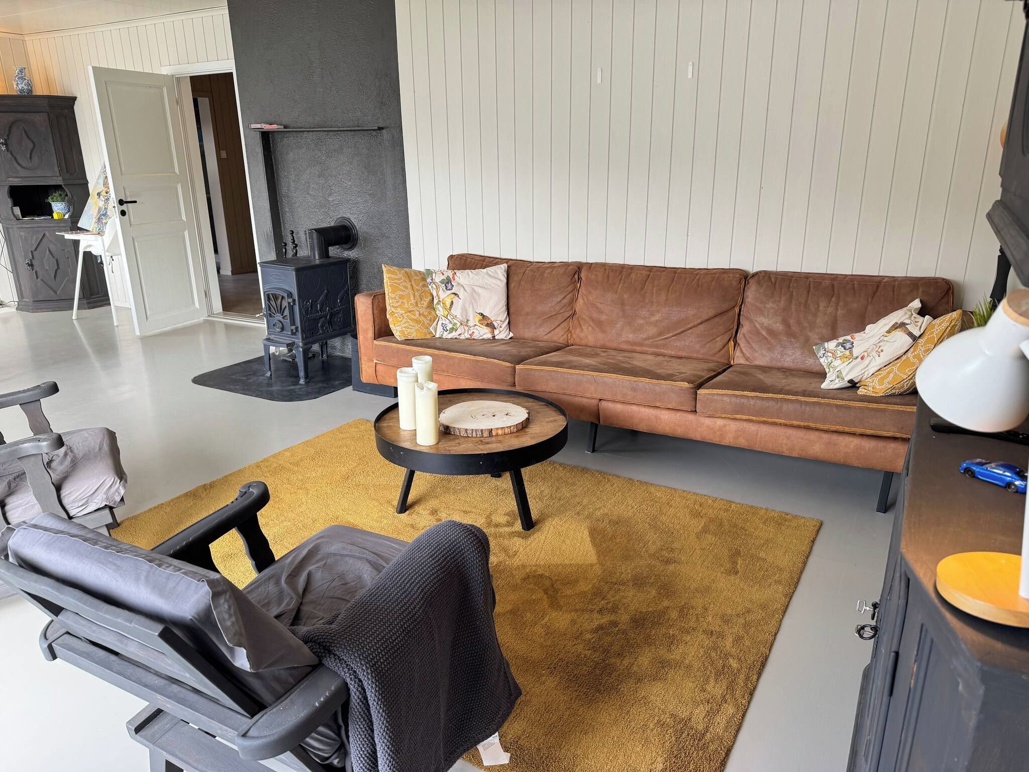 A modern living room with a brown leather sofa, a round coffee table, and a black office chair.