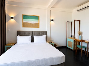 Une chambre d’hôtel avec un grand lit, une table de chevet, un bureau avec une chaise, un miroir et une œuvre d’art accrochée au mur.