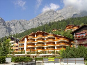 Ein mehrstöckiges Hotel mit Balkonen vor einer Bergkulisse.