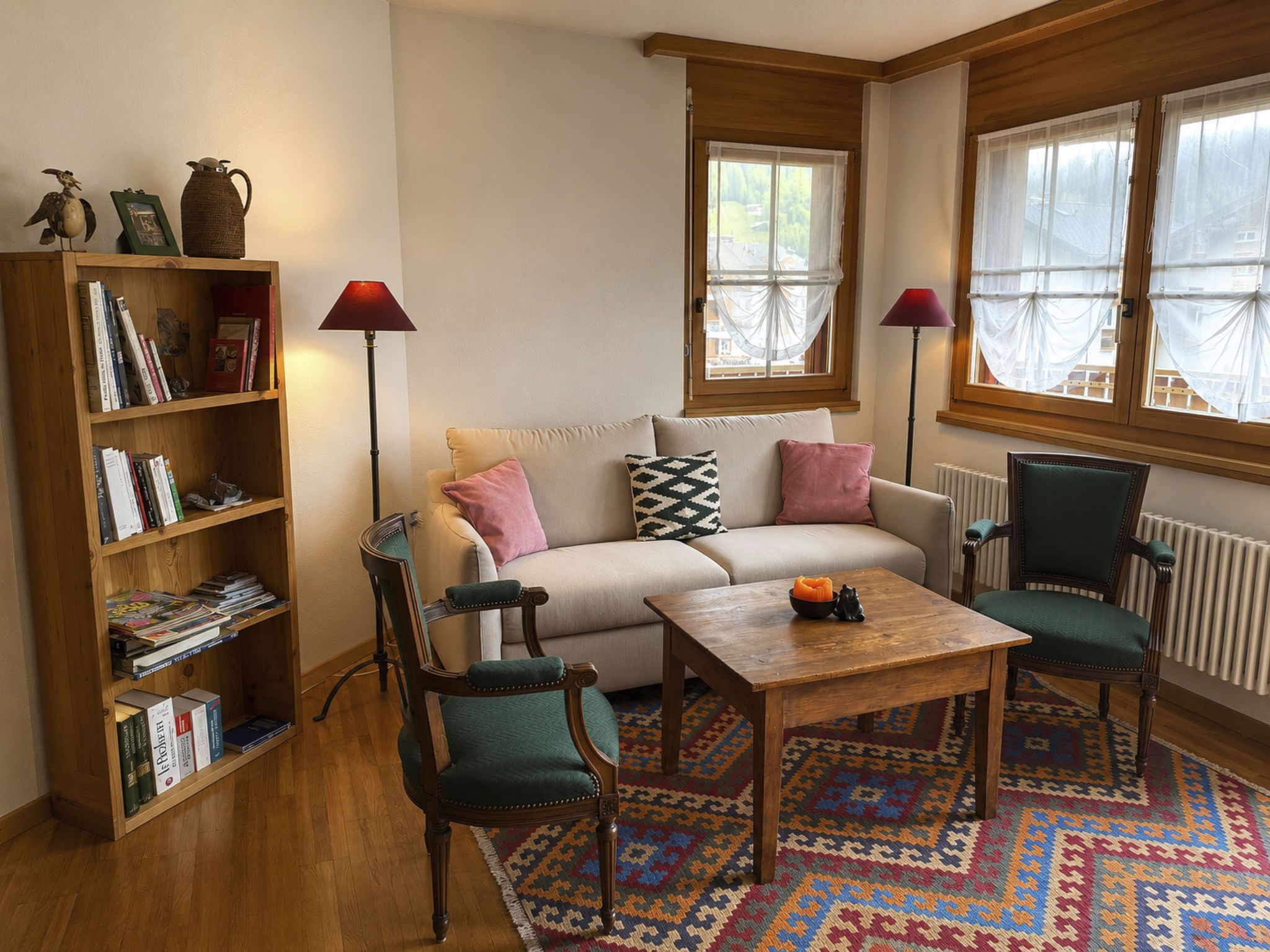 Een gezellige woonkamer met een bank, twee fauteuils, een salontafel, een boekenkast en een kamerkleed met een patroon.
