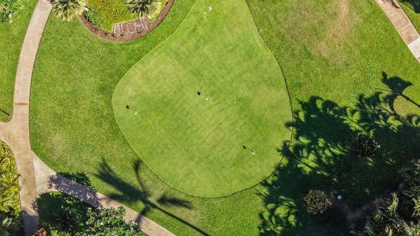 A golf course with a putting green, surrounded by a walking path and greenery. - Beach Front & Just Steps to Pools & Hot Tub (Kihei)