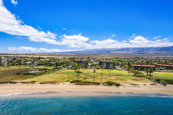 Resort costeiro com propriedades na praia, campo de golfe e vista para montanhas distantes.