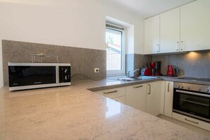 Eine moderne Küche mit integriertem Mikrowellenherd, Backofen und einem roten Wasserkocher.