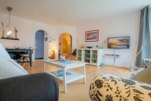A living room with a sofa, a coffee table, a TV, and a bookshelf. - 6 in the house at Blanker-Hans-Weg 5 (ID 084) (St. Peter-Bad)