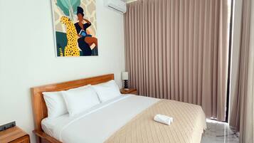 A hotel room with a bed, a nightstand, a lamp, a painting, and a window with curtains.