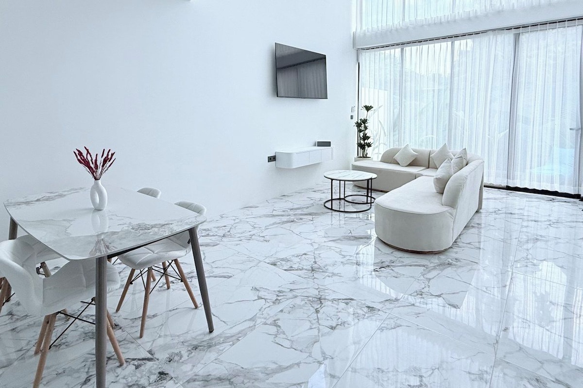 Um interior moderno com área de refeições, sofá e janelas amplas.